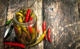 Pickled hot chili peppers in glass jar. photo