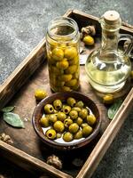 Olive oil with pickled olives on an old tray. photo