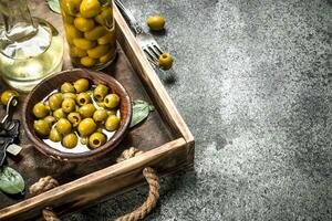 Olive oil with pickled olives on an old tray. photo