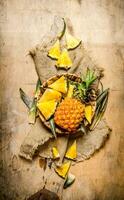 Fresh pineapples, whole and sliced in a basket on old fabric. photo