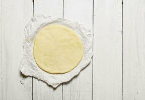 The rolled out pizza dough on the paper. photo