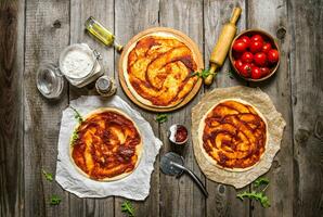 Three pizzas spread tomato sauce the ingredients. photo