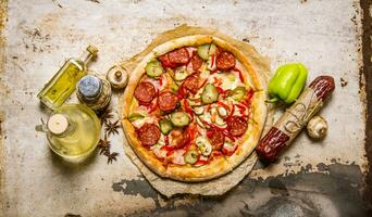 Delicious pizza with ingredients - salami, peppers, mushrooms and olive oil. photo