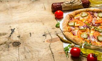 Pizza with bacon and salami on paper. On wooden table. photo