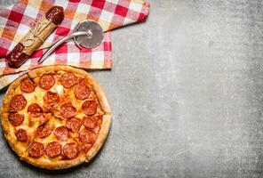 Pepperoni pizza with salami and cheese. On stone table. photo