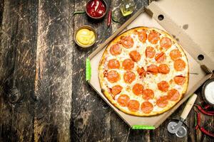 Pepperoni pizza in a box with a knife. photo