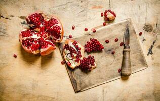 Cut ripe pomegranate on the old Board with a knife. photo