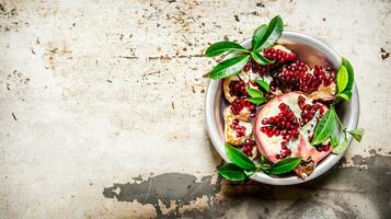 Pieces pomegranate with leaves in a Cup top view. photo