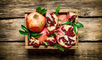 Fresh pomegranates in an old box with leaves. photo