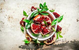 Pieces pomegranate with leaves in a Cup top view. photo