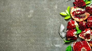 Pieces of ripe pomegranate with leaves and ice. photo