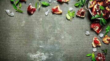 Pieces of ripe pomegranate with leaves and ice in a bowl. photo