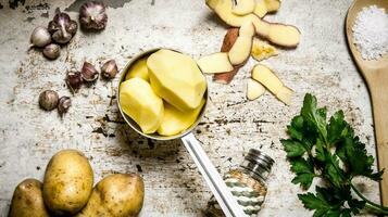 The concept of a peeled potato in the pot on the rustic background . photo