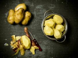 The concept of wet peeled potatoes on the stone table . photo