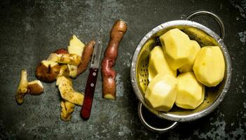 The concept of wet peeled potatoes on the stone table . photo