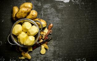 The concept of wet peeled potatoes on a stone background . Free space for text. photo