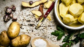 The concept of peeled potatoes in a bowl on the rustic background . photo