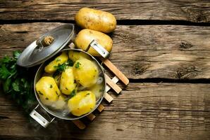 Boiled potatoes with herbs on wooden table . Free space for text. photo