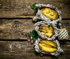 Baked potatoes in foil on a wooden table . Free space for text. photo
