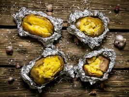 Baked potatoes in foil on a wooden table . photo