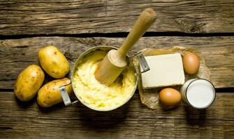 Ingredients for mashed potatoes - eggs, milk, butter and potatoes on wooden background. photo