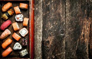 japonés alimento. Sushi y rollos Mariscos en el antiguo bandeja. en el antiguo de madera antecedentes. foto