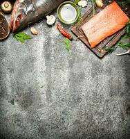 Raw fish. Salmon fillet with herbs and spices. On rustic background. photo