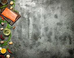 Raw fish. Salmon fillet with herbs and spices. On rustic background. photo