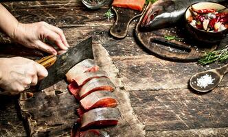 crudo pez. corte Fresco salmón De las mujeres manos. en el antiguo de madera mesa. foto