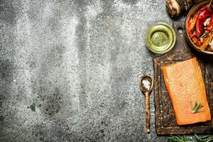 Raw fish. Salmon fillet with herbs and spices. On rustic background. photo