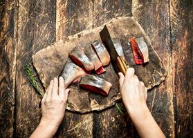 crudo pez. corte Fresco salmón De las mujeres manos. en el antiguo de madera mesa. foto