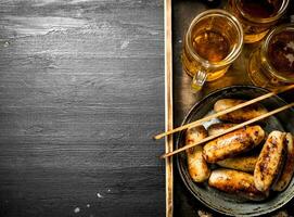 Sausages with beer on a wooden tray. photo