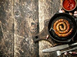 Sausage in a frying pan with tomato sauce and garlic. photo