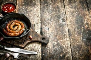 Sausage in a frying pan with tomato sauce and garlic. photo