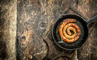 Sausage in a frying pan on the board. photo