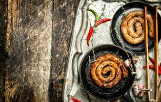 Sausages in pans on a steel tray with hot chili peppers. photo