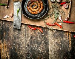 fragrant sausage in a frying pan with a branch of thyme. photo