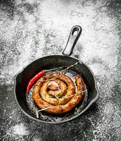 Sausage in a frying pan with hot peppers. photo