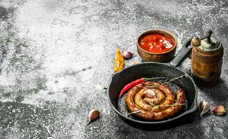 Sausage in a frying pan with hot peppers, garlic and sauce. photo