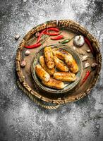 Sausages in an old pan with hot peppers. photo