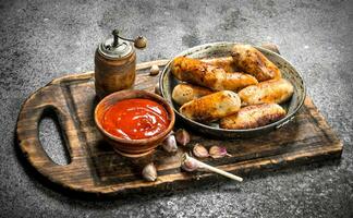 Sausages with tomato sauce on the board. photo