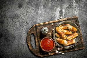 Sausages with tomato sauce on the board. photo