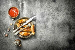 Sausages in a frying pan with tomato sauce. photo