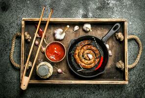 Sausage in a frying pan with garlic, pepper and tomato sauce. photo