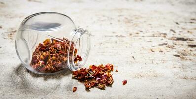 Dried red Chili peppers in the jar. On rustic background. photo