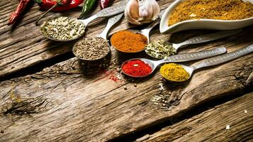 Different kinds of spices in spoons. On wooden background. photo