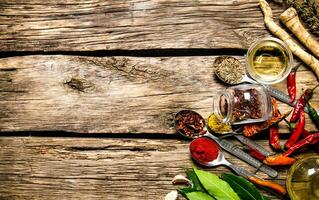 A lot of different spices in spoons with herbs and garlic. photo