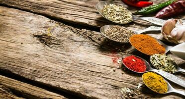 Different kinds of spices in spoons. On wooden background. photo