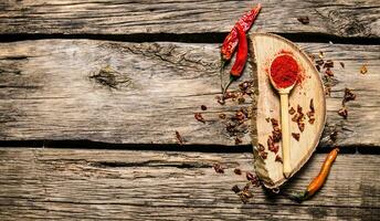 Dried and ground red chili pepper on oak stand. photo