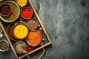 Ground spices in bowls on a wooden tray. photo